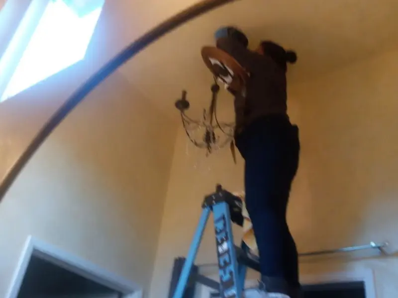 Electrician installing a chandelier in a Petersburg residence